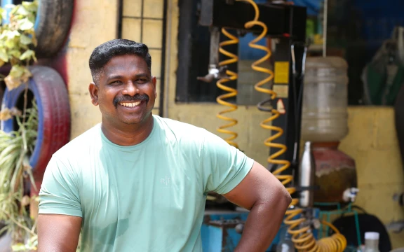 Friendly mechanic at Aditya Motor Works & Car Wash with tools in background.