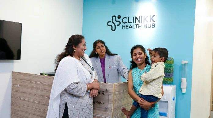 Happy family interacting with clinic staff at the reception of Clinikk Health Hub.